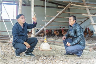    穆海彬（左）教村民如何开展科学养殖。