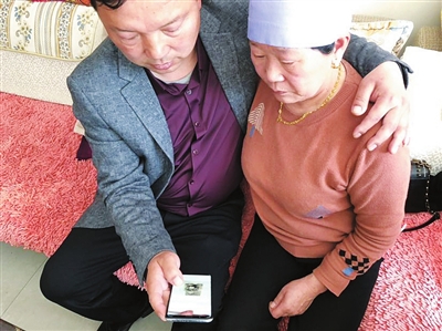 徐大雷与母亲在手机上翻看自己小时候的照片。本报记者  黄英  摄