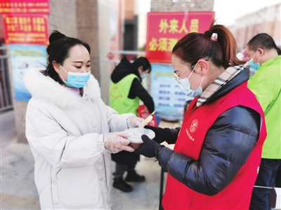 社区工作人员将腊八粥送到志愿者手中。王雨  摄