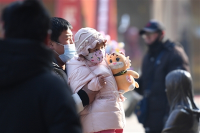     街头，孩子抱着老虎玩偶。